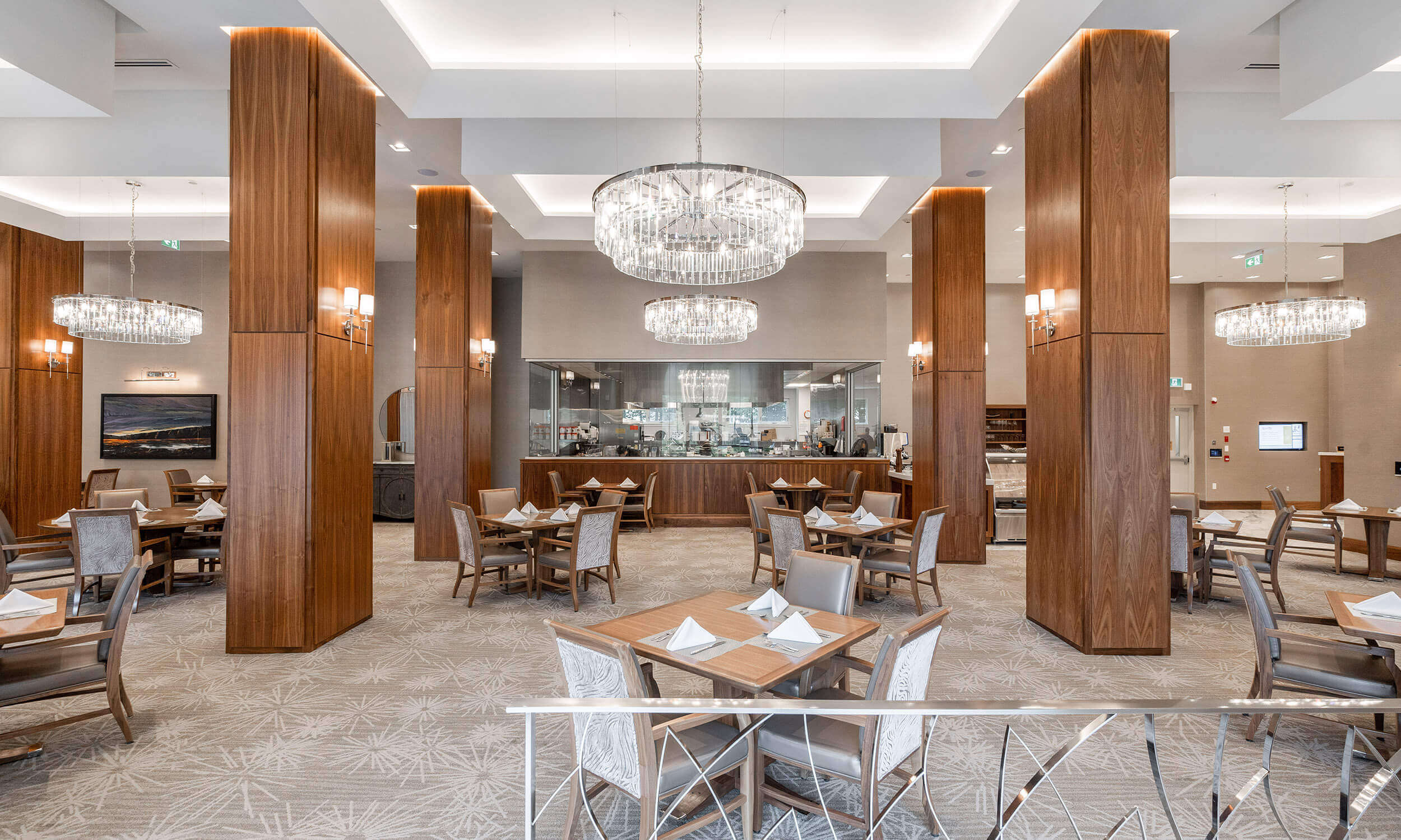 Dining room in Parkland facility with set tables and bar in background, high ceilings with a chandeliers, and grey carpeted floorsDining room in Parkland facility with set tables and bar in background, high ceilings with a chandeliers, and grey carpeted floors