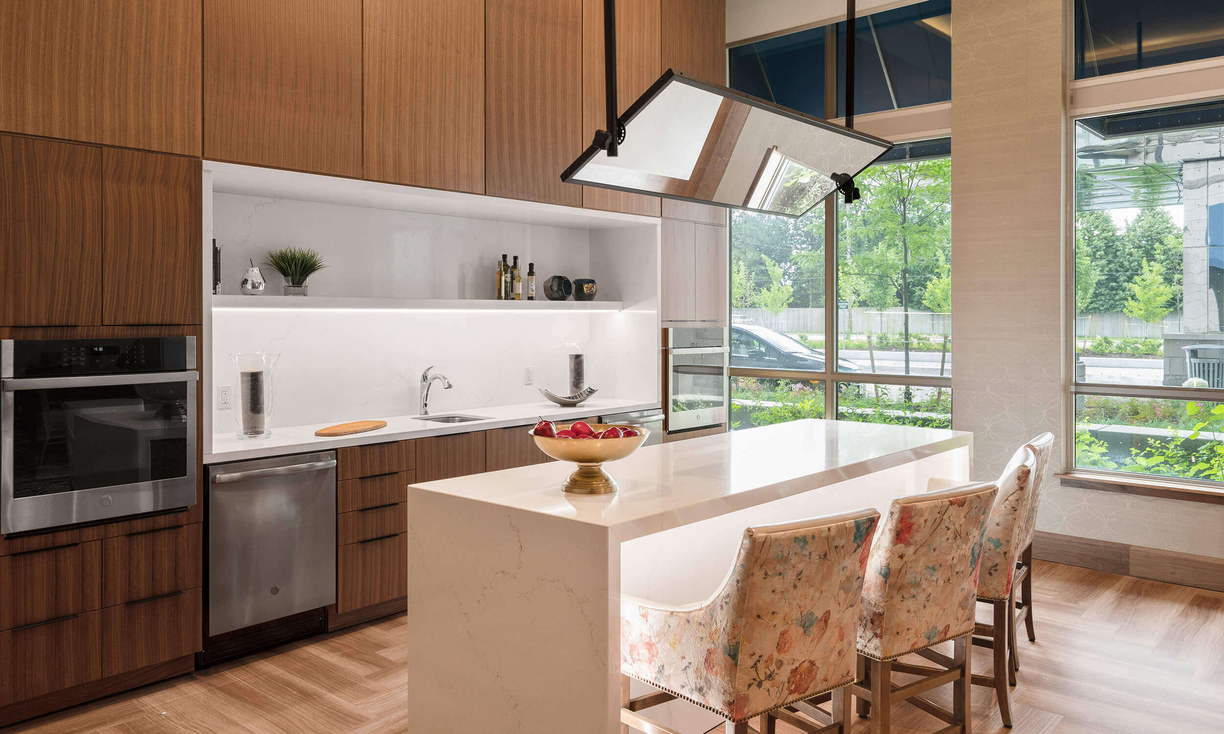 Large open-concept kitchen with  tall wooden cabinets and marble island with three chairs