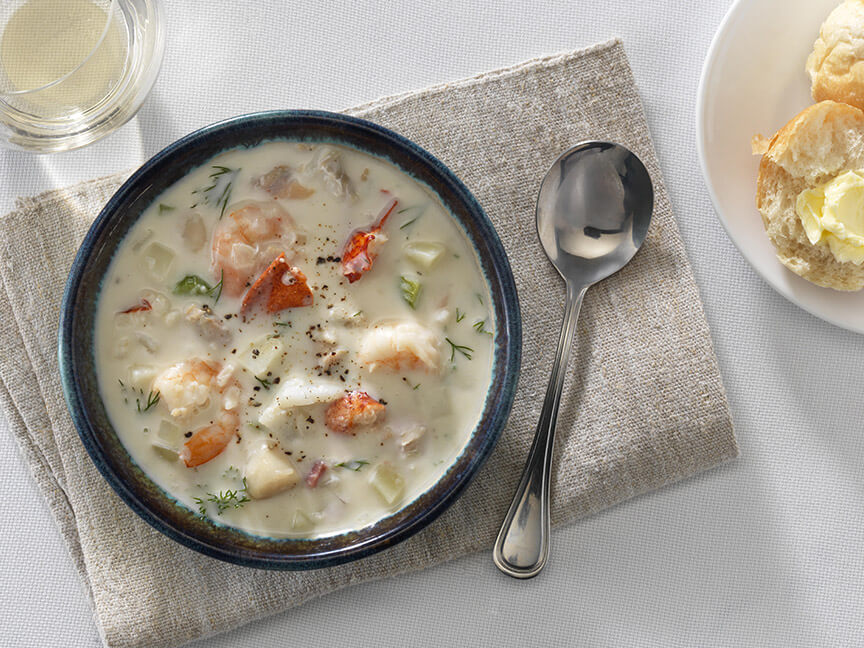 Bowl of chowder soup with glass of wine and dinner roll