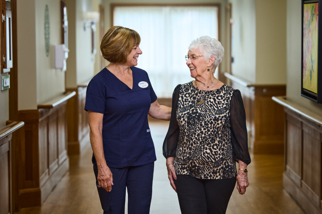 Staff and resident walking down a hallway.